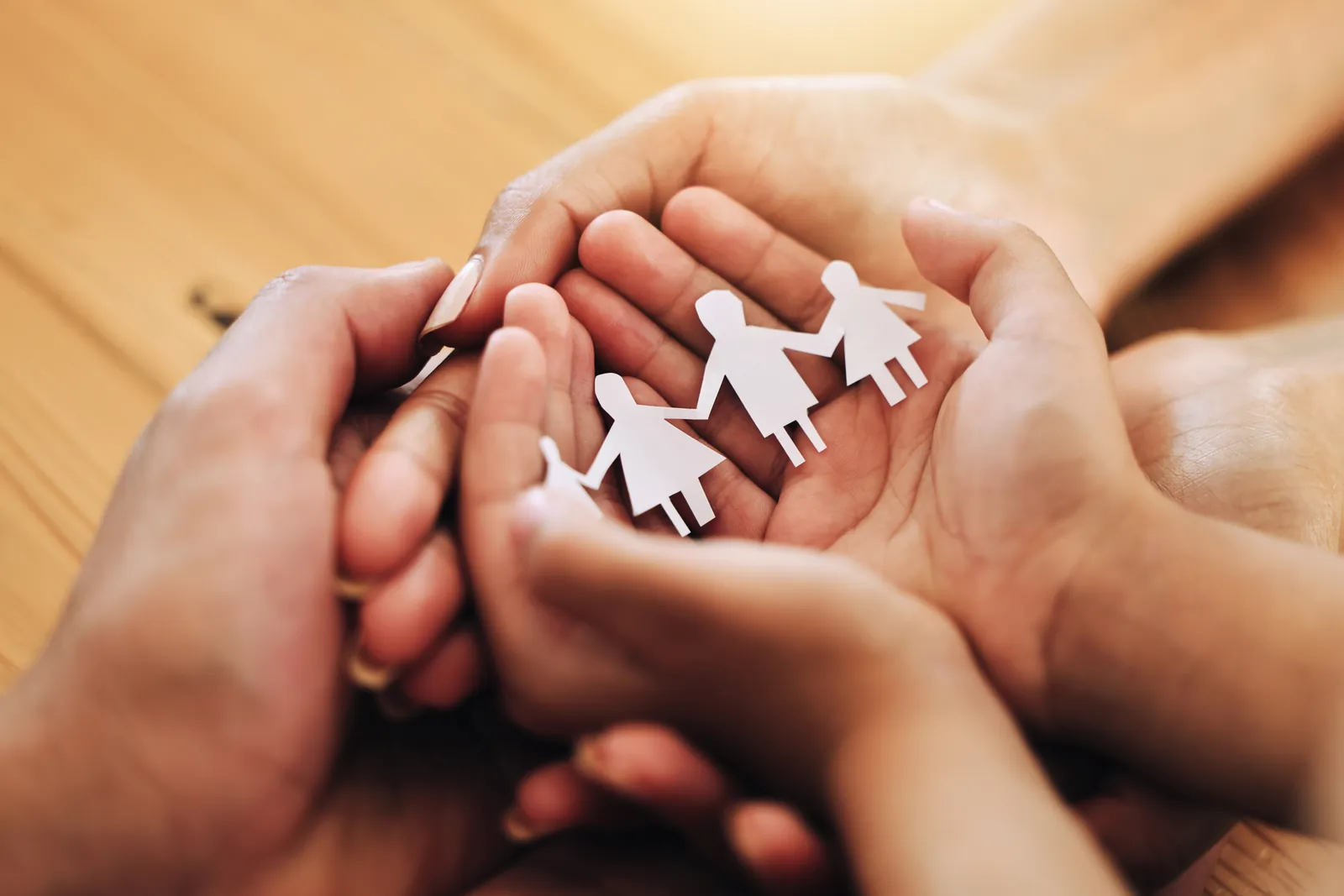 Hands holding paper cutouts representing family