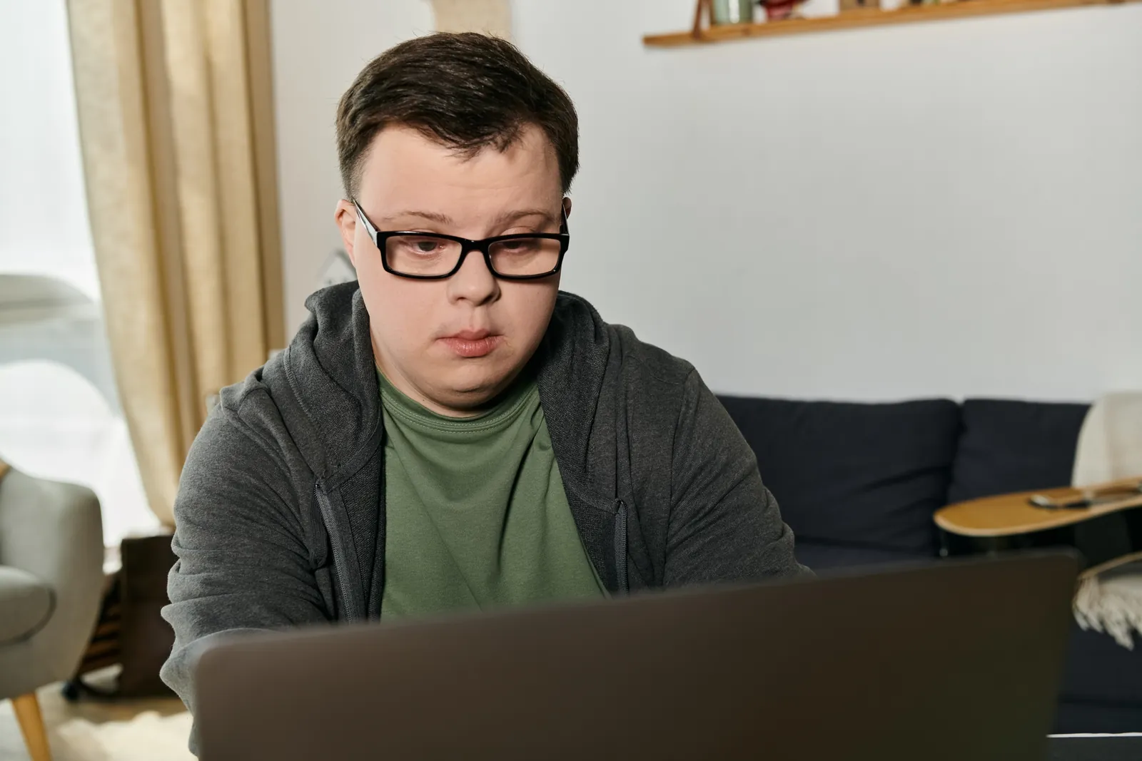 A man with an intellectual disability works on his laptop in a living room