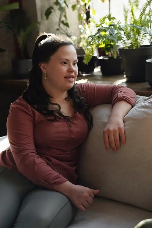 A woman with IDD sits on the couch in her living room