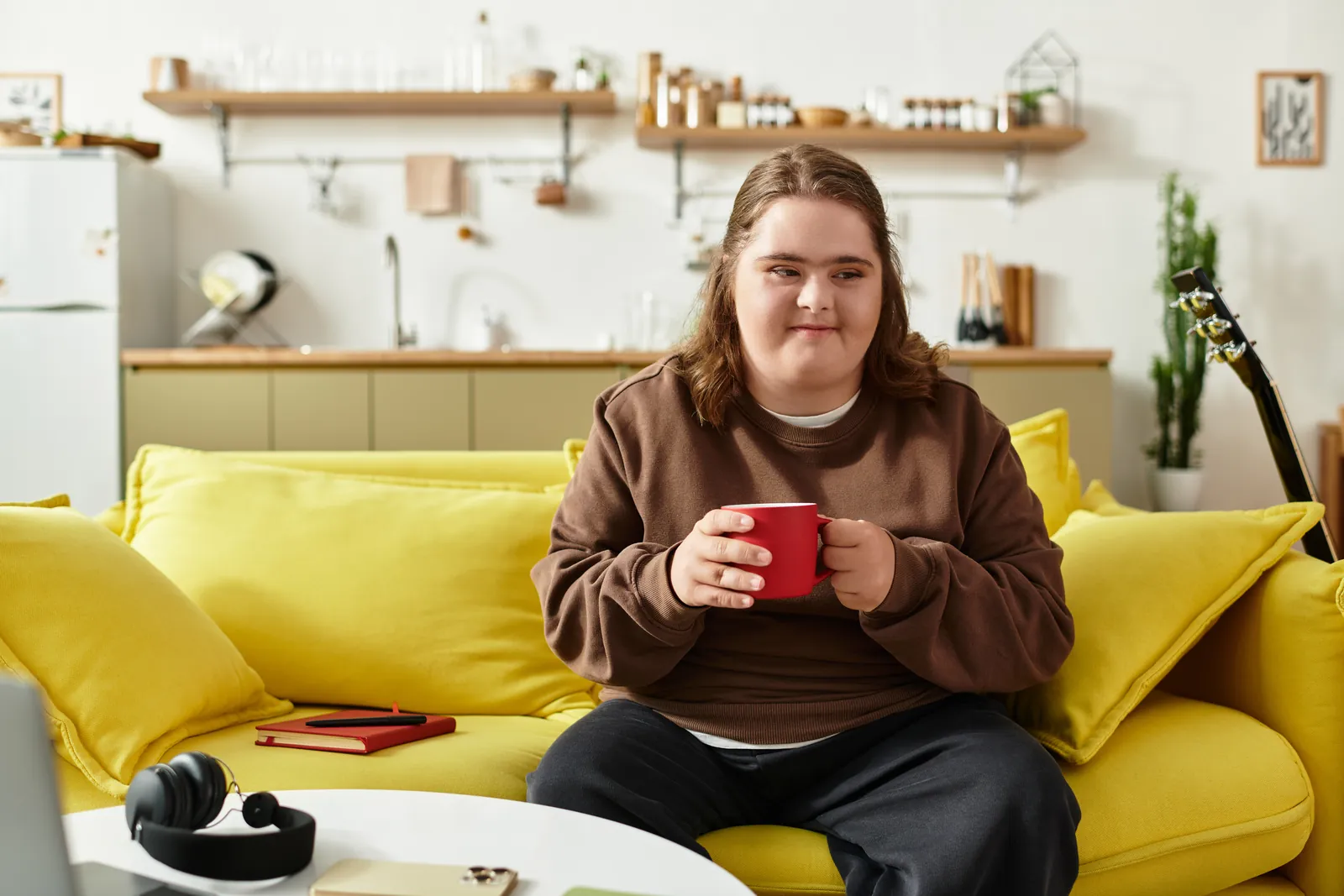 A woman with an intellectual disability sits on her couch with a cup of coffee
